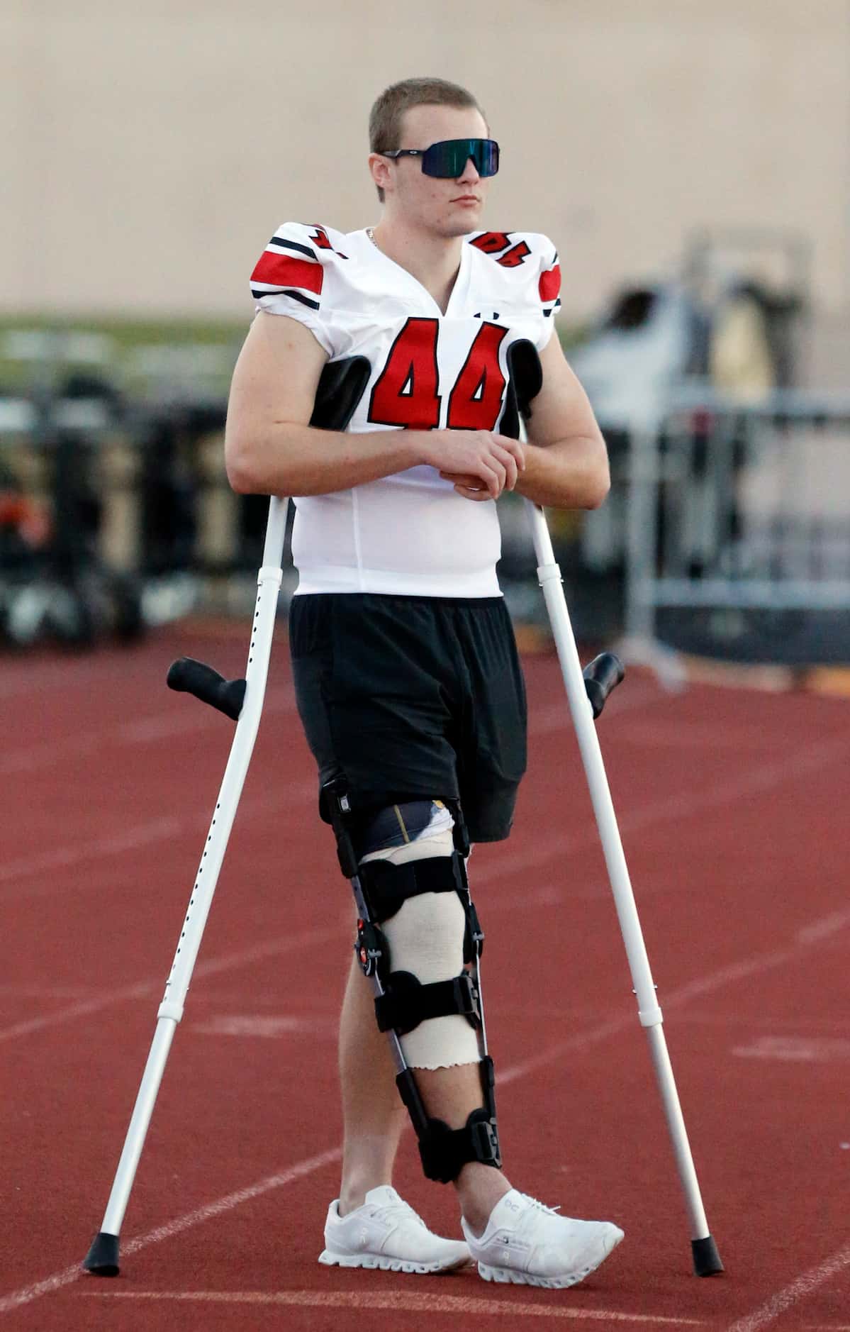 Injured Rockwall Heath player Cade Gemmell (44), relaxes in sunglasses and crutches, watches...