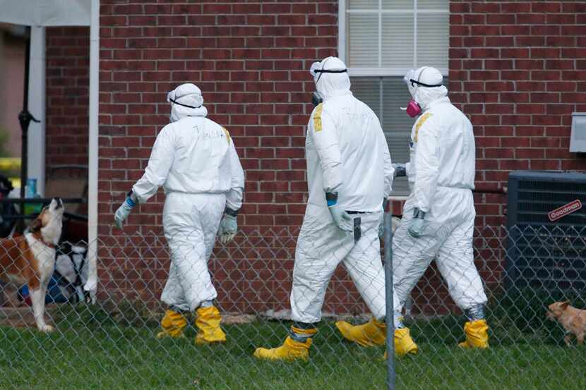 A dog barks at federal agents wearing hazmat suits as they inspect the grounds around the...