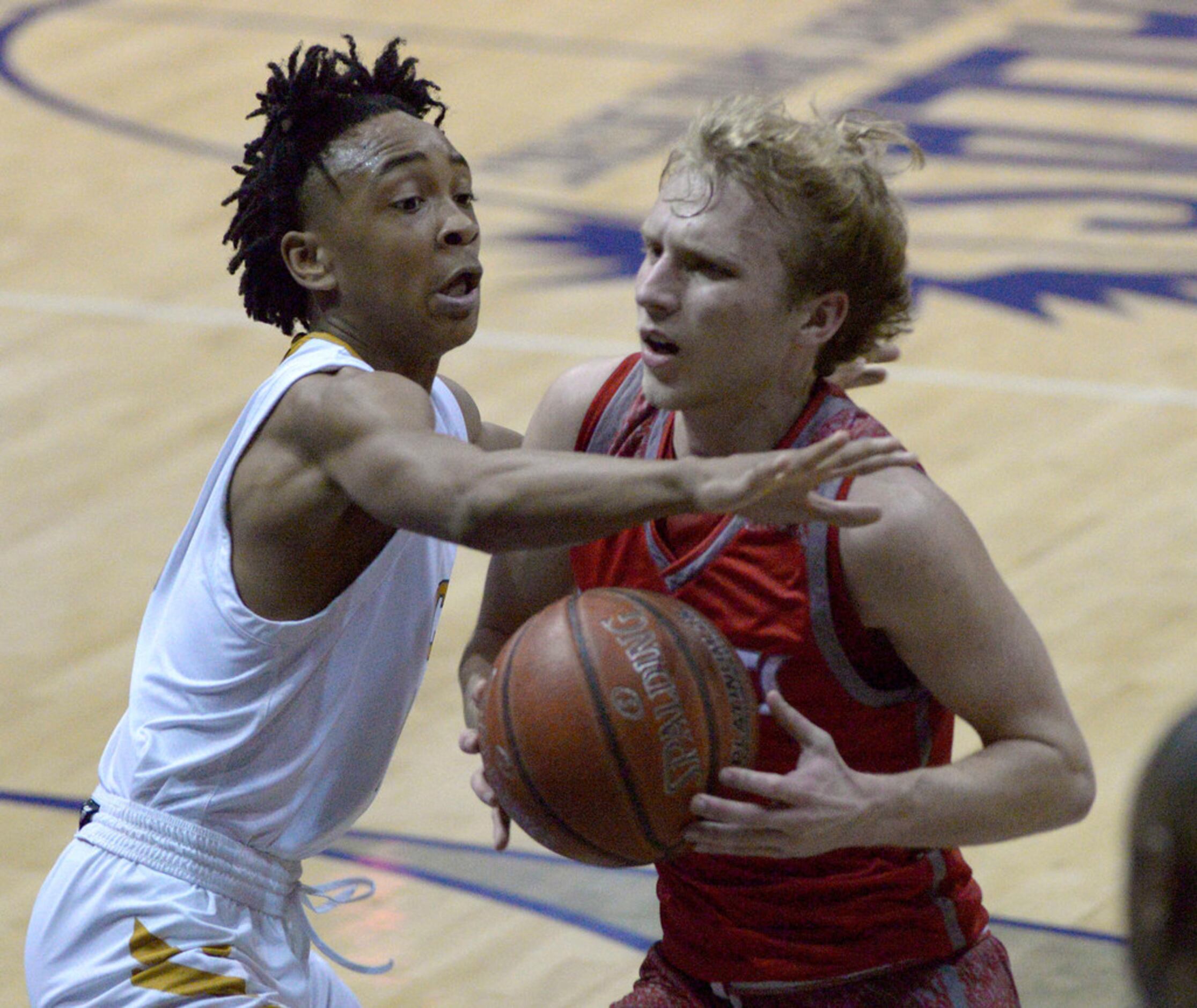 Woodrow Wilson's Cade Ross (in red) drives to the basket on South Oak Cliff's DeJuan Leffall...
