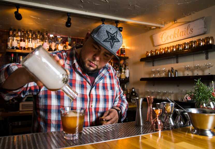 Mixologist Manny Casas pours the smoke-infused cocktail into a glass with ice.