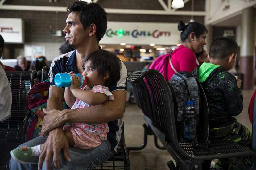 Dennis Espinoza holds his daughter Carmine, 13 months, at a bus station in Phoenix on July...