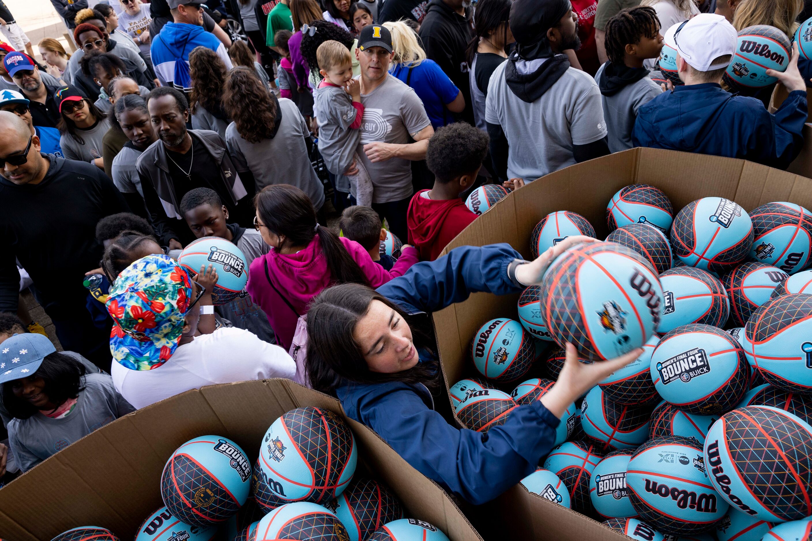 Volunteer Kiera Burns hands out basketballs before people dribble their way from City Hall...