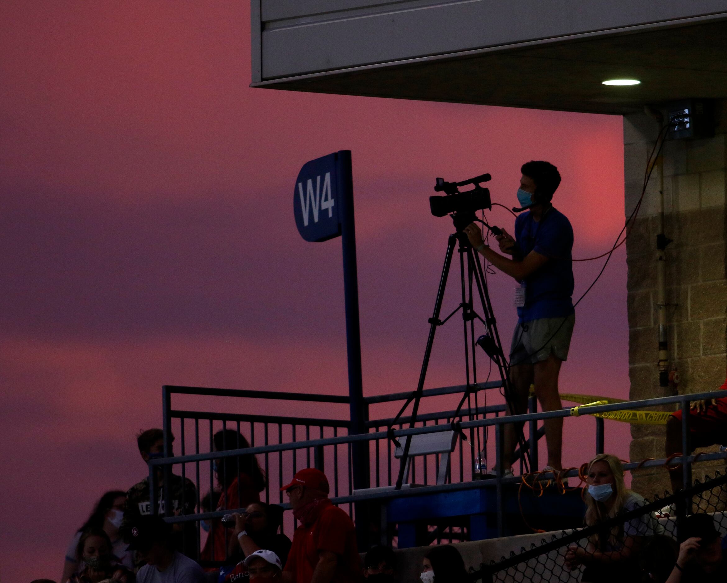A videographer is silhouetted against a setting sun during first half action of the...
