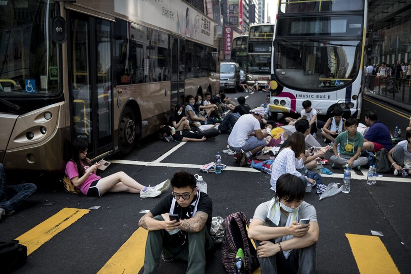 Pro-democracy protesters rest around empty buses as they block off Nathan Road, a major...