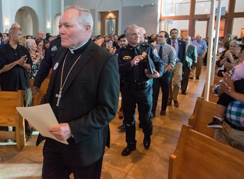 Rev. Edward J. Burns is followed by a procession of clergy, law enforcement officials and...