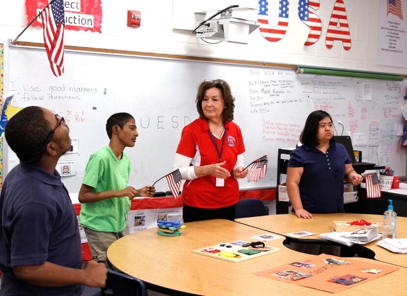 Carolyn Dreyer waves the American flag with some of her students during the national anthem...