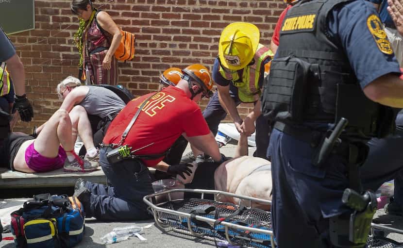 Injured people receive first aid after a car ran into a crowd of protesters in...