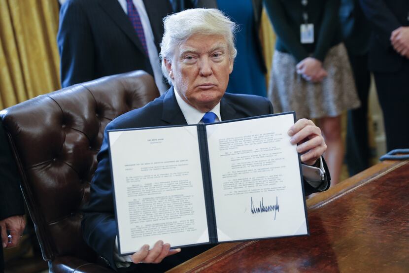 President Donald Trump displays one of five executive orders related to the oil pipeline...