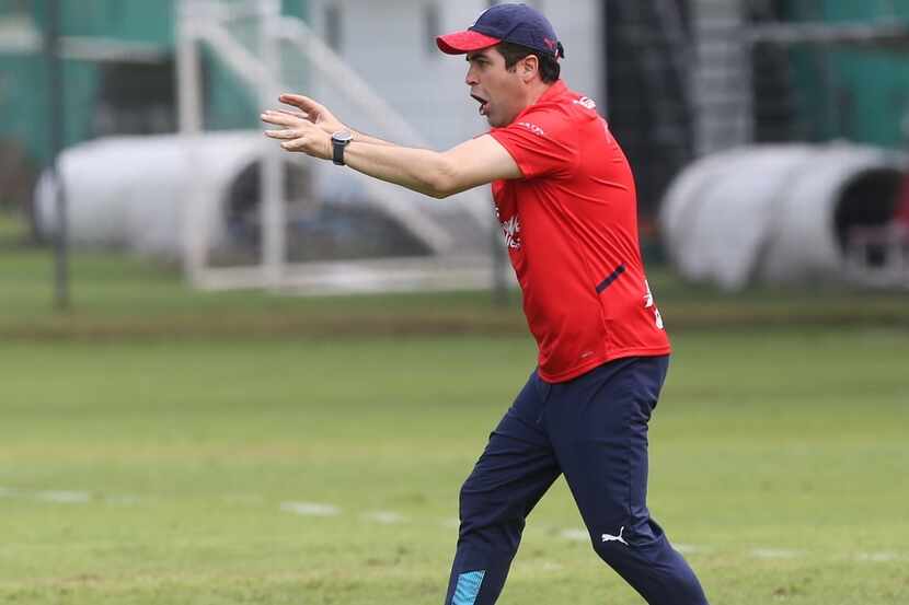 El técnico interino de Chivas de Guadalajara, Michel Leaño, da instrucciones a su equipo que...