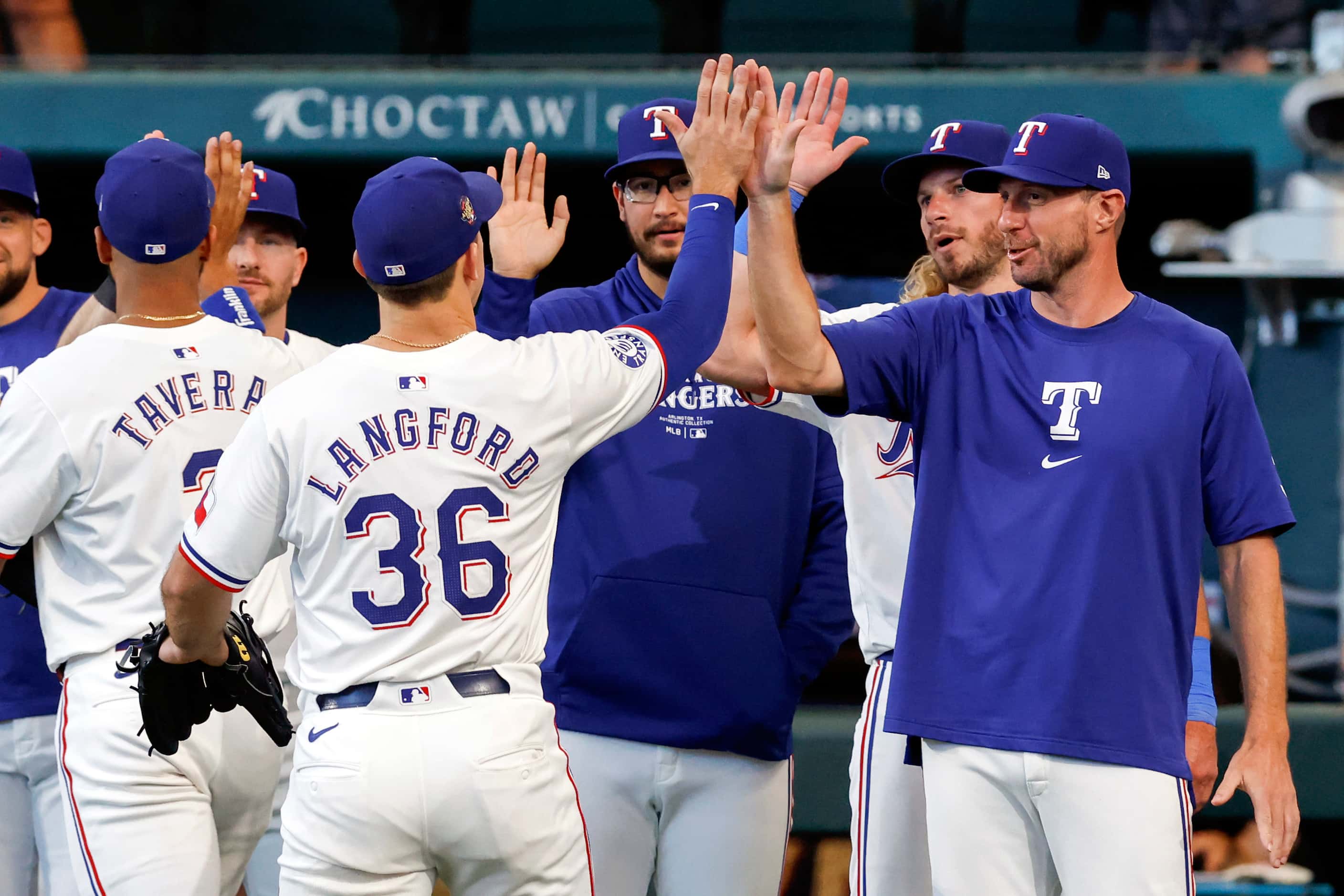 Texas Rangers starting pitcher Max Scherzer high-fives left fielder Wyatt Langford after an...