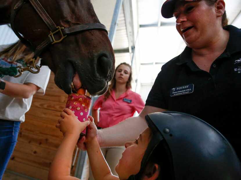 Occupational therapist Joanna Rubenfield helps Mora Wolf feed a carrot to Hombre after their...