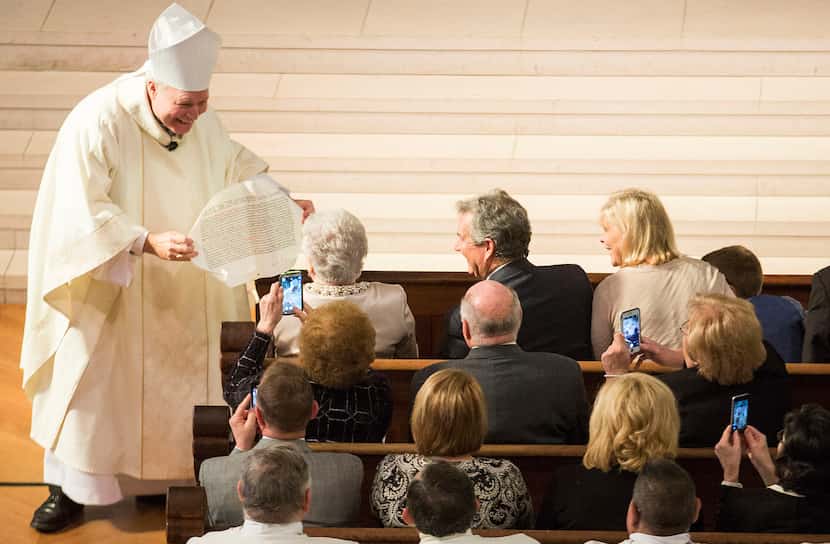 Bishop Edward J. Burns show off the papal bull, a letter declaring him the Bishop of Dallas,...