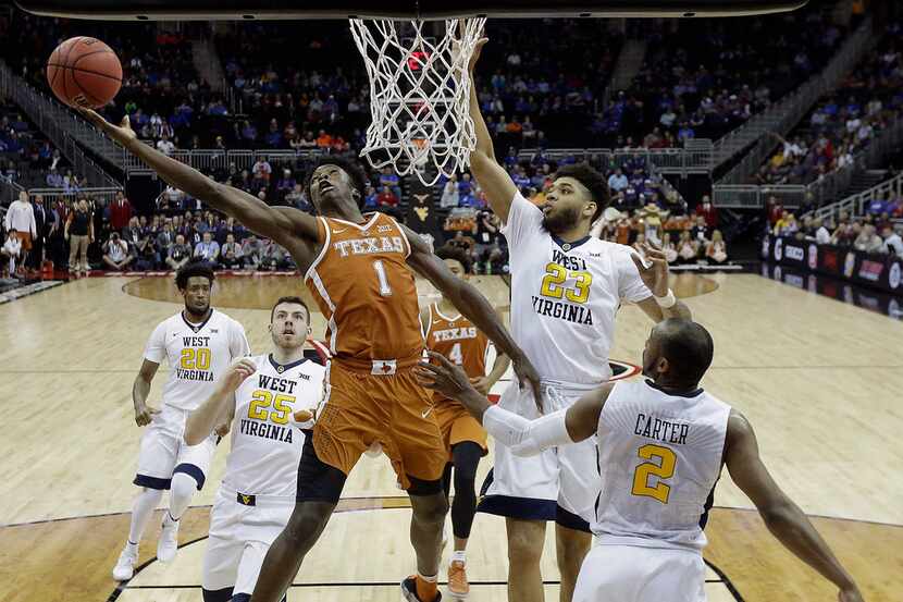 Texas' Andrew Jones (1) gets past West Virginia's Esa Ahmad (23) to shoot during the first...