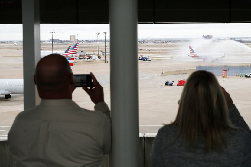 Family and American Airlines employees capture the airplane getting a water salute before...