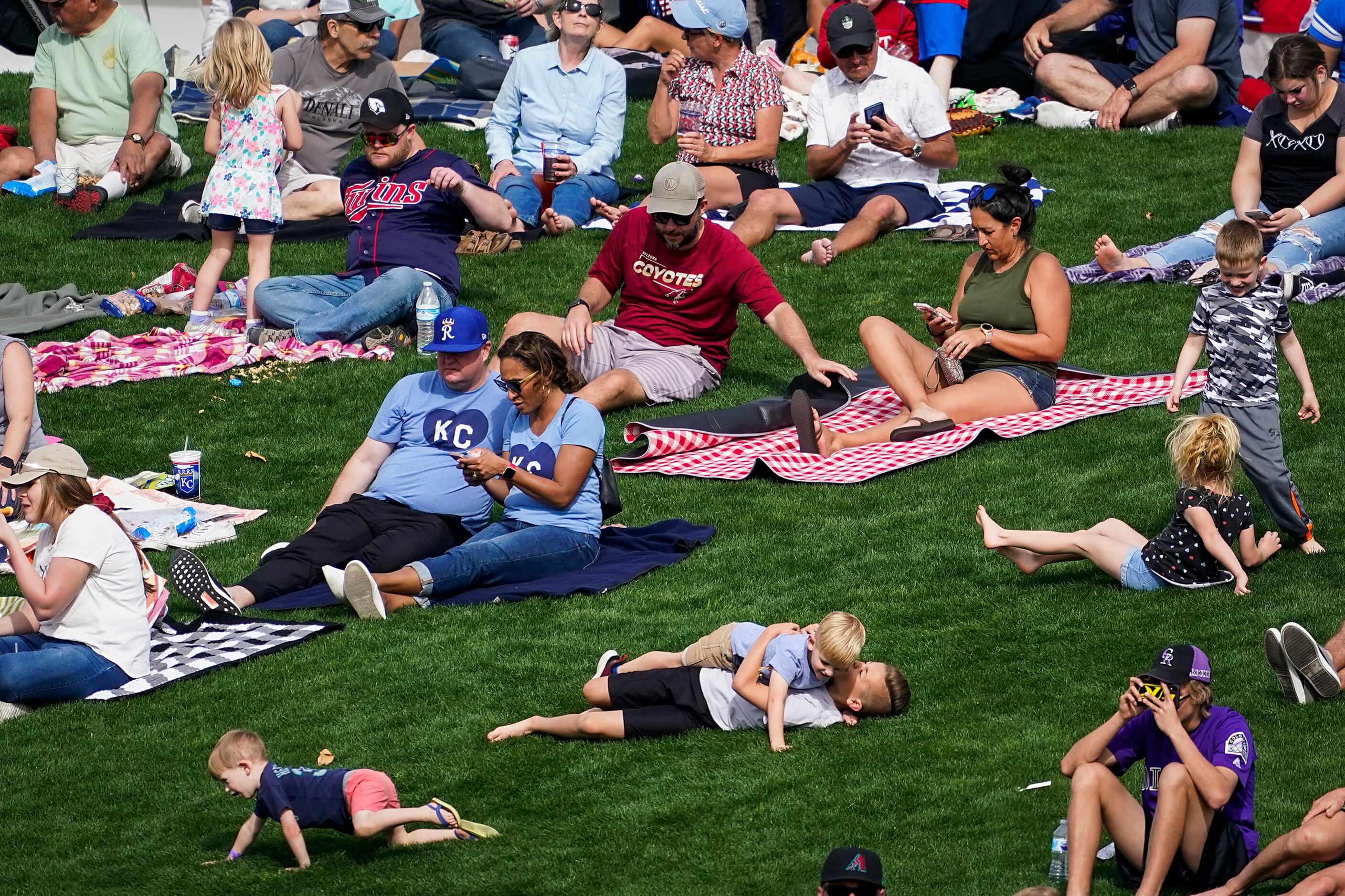 Young fans tumble on the outfield berm during the seventh inning of a spring training game...