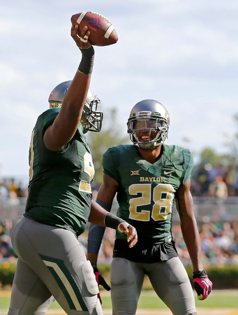 Baylor defensive tackle Ira Lewis (97) holds up the ball next to safety Orion Stewart (28)...