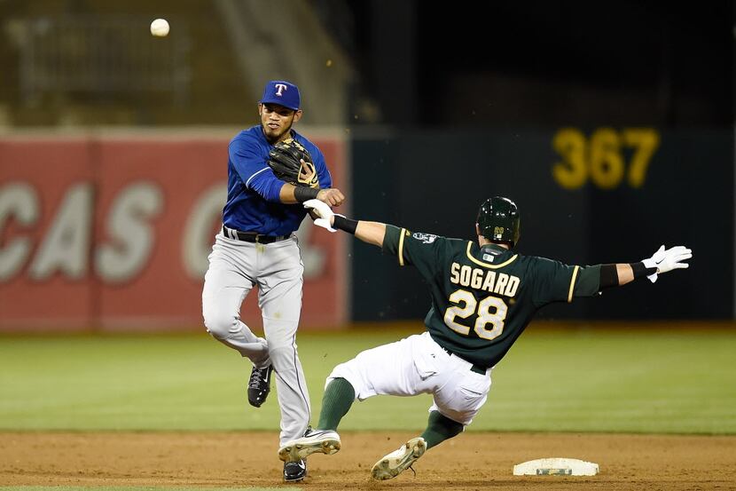Luis Sardinas #3 of the Texas Rangers completes the double-play over the top of Eric Sogard...