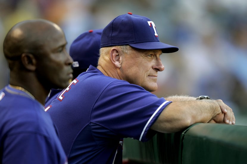 Texas Rangers first base coach Gary Pettis, left, and bench coach Art Howe, center, watch...