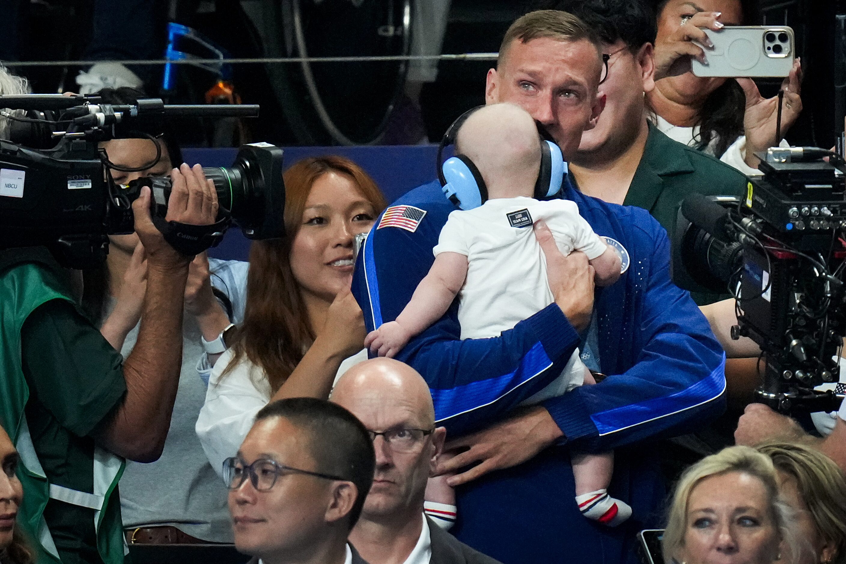 Caeleb Dressel of the United States holds his son August as he celebrates after winning the...