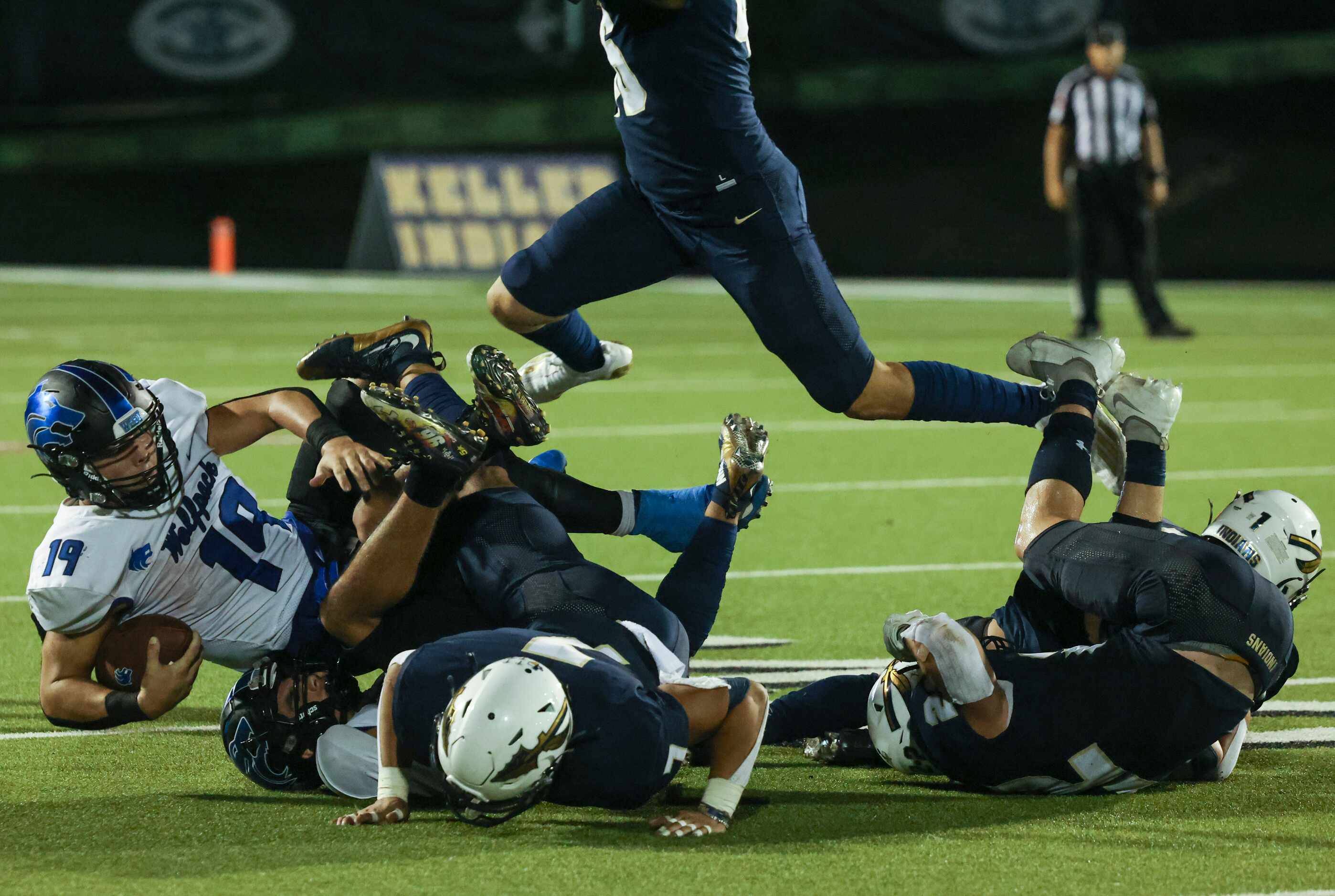 Plano West Senior High Vance Feuerbacher (19) falls over the pileup of players during the...