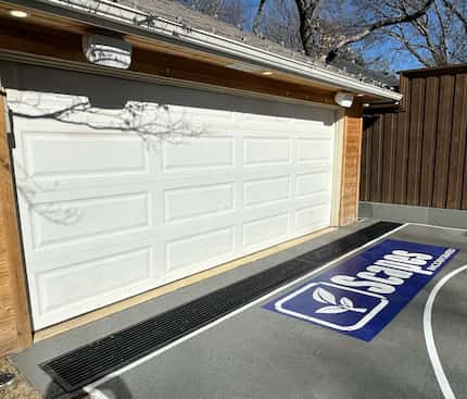 Garage driveway with wrought-iron drain installed to keep out rainwater.