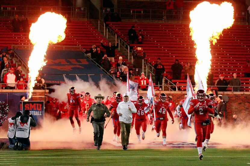 The SMU team enters the playing field through fire and smoke before the first half against...