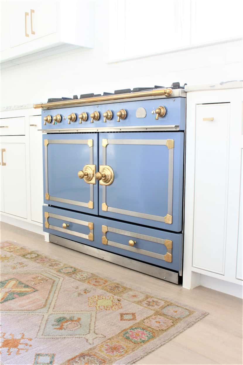 An all-white kitchen features a blue range.