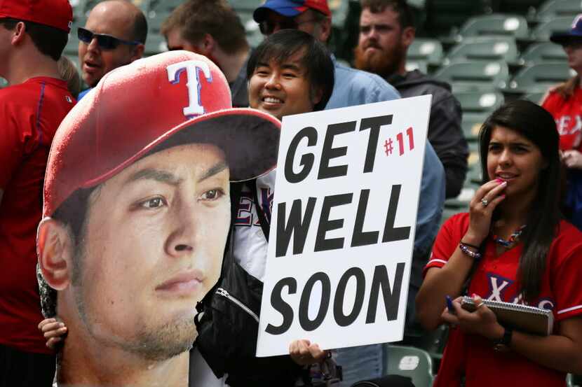 Fans hold a sign supporting injured Texas Rangers pitcher Yu Darvish (11) during batting...