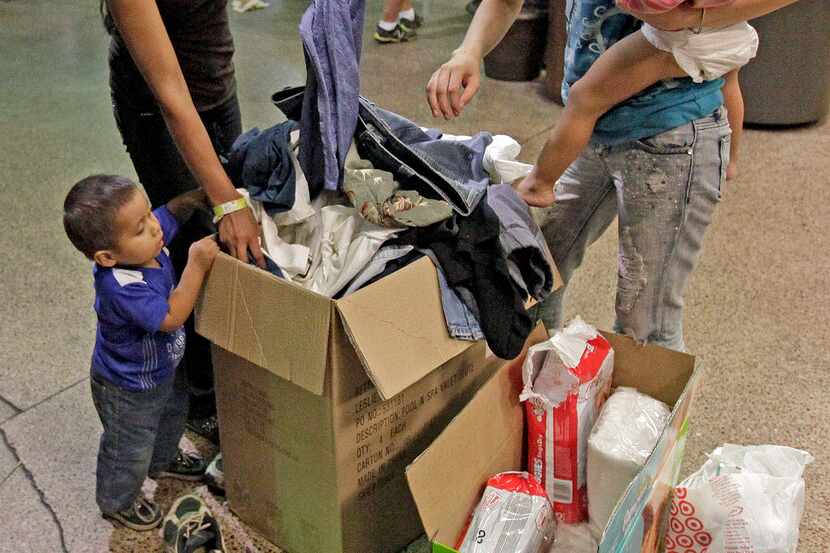 Women and children look through a box of cloths that were donated by volunteers at the...