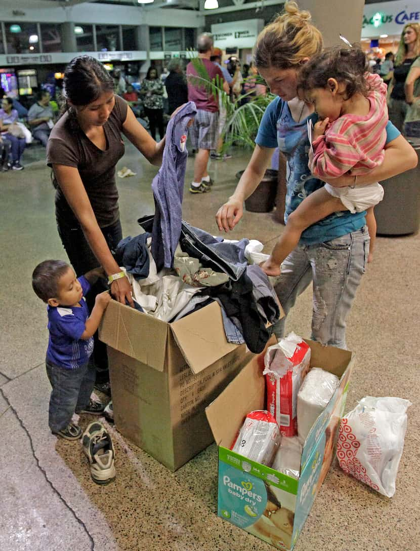 Women and children look through a box of cloths that were donated by volunteers at the...