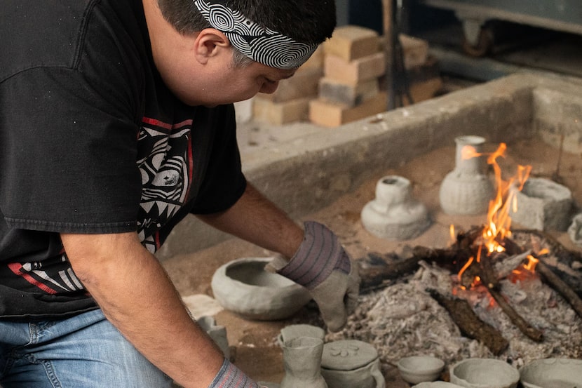 Chase Kahwinhut Earles tending to an open bonfire, which he uses to fire his ceramics, at a...