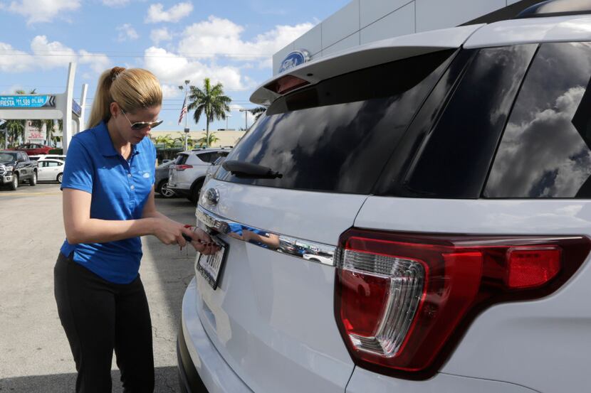 In this Tuesday, Jan. 17, 2017, photo, Ford sales consultant Yanaisis Milian removes the...