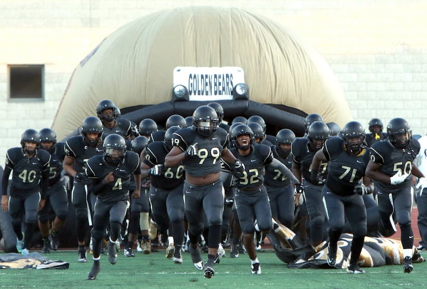 Members of the South Oak Cliff Golden Bears football team rush out of their team's...