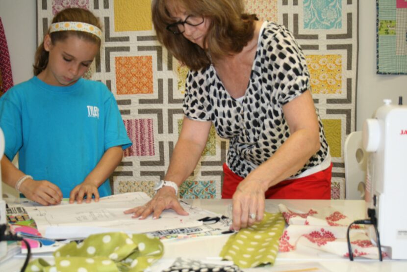 Michelle Kitto helps Elise Little, 9, pin her pattern to the fabric she chose during a...