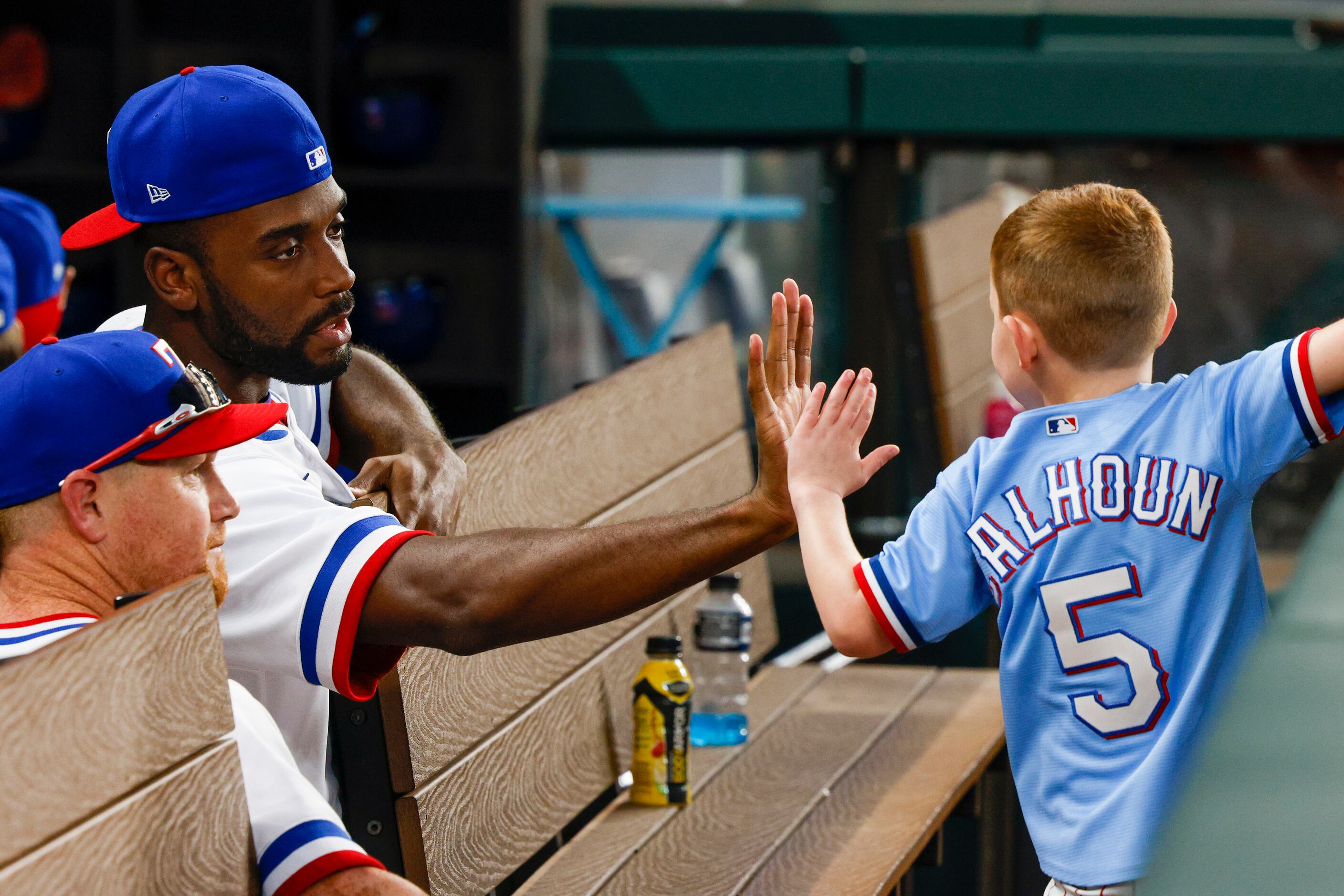 Texas Rangers relief pitcher Taylor Hearn high-fives Knox Calhoun, son of right fielder Kole...