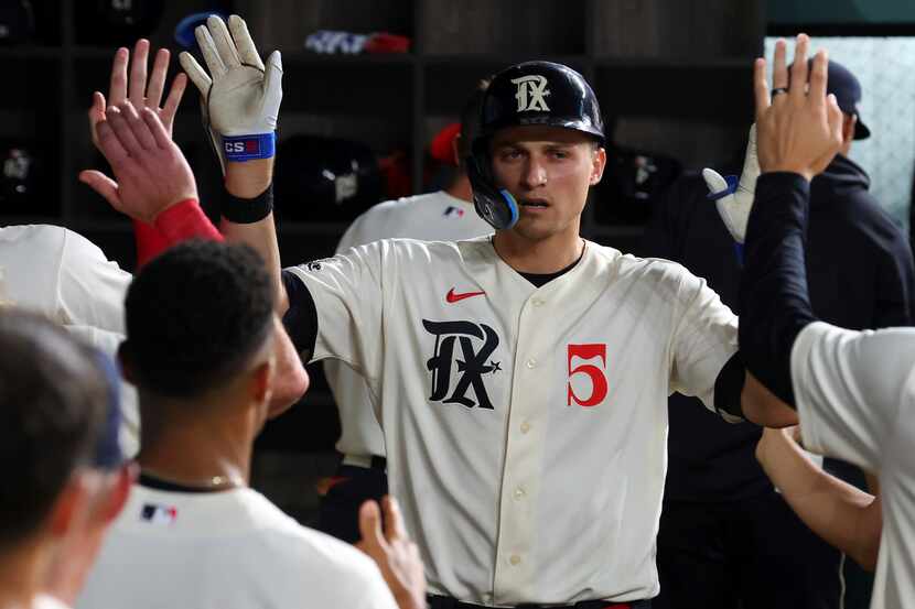 Texas Rangers' Corey Seager (5) is celebrated in the dugout after a solo home run against...