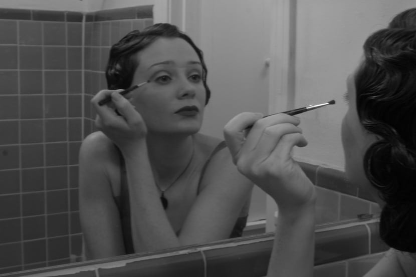 Singer-songwriter Kristy Kruger looks into the mirror while putting on makeup.