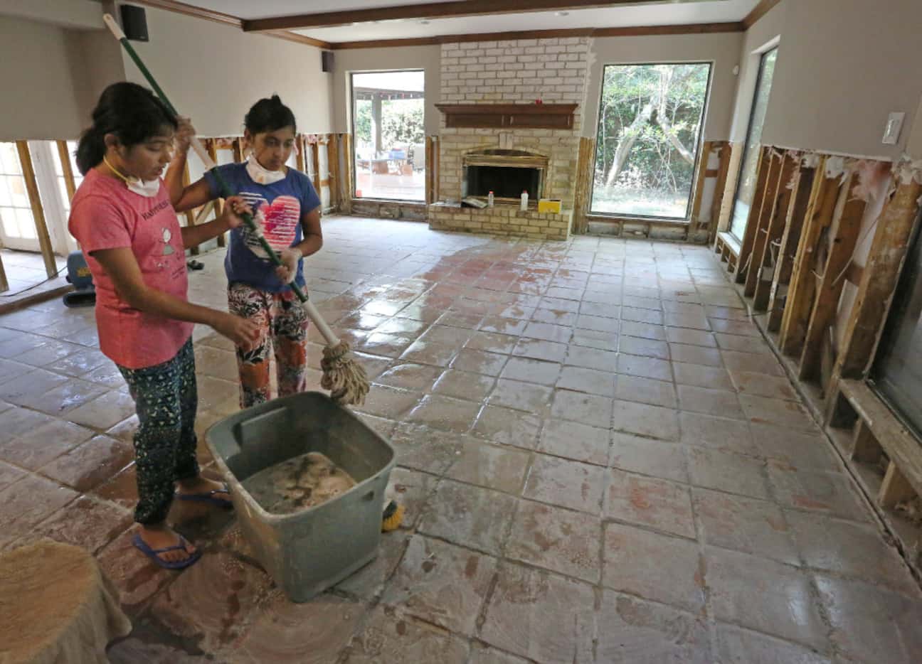 Twin sisters Saloni and Sugani Singh, 10, share mopping duties as they work to clean up...