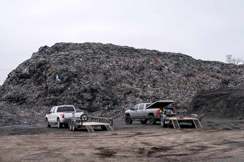 Pickups sit next to the pile of roofing shingles known as Shingle Mountain  on Dec. 15, 2020...