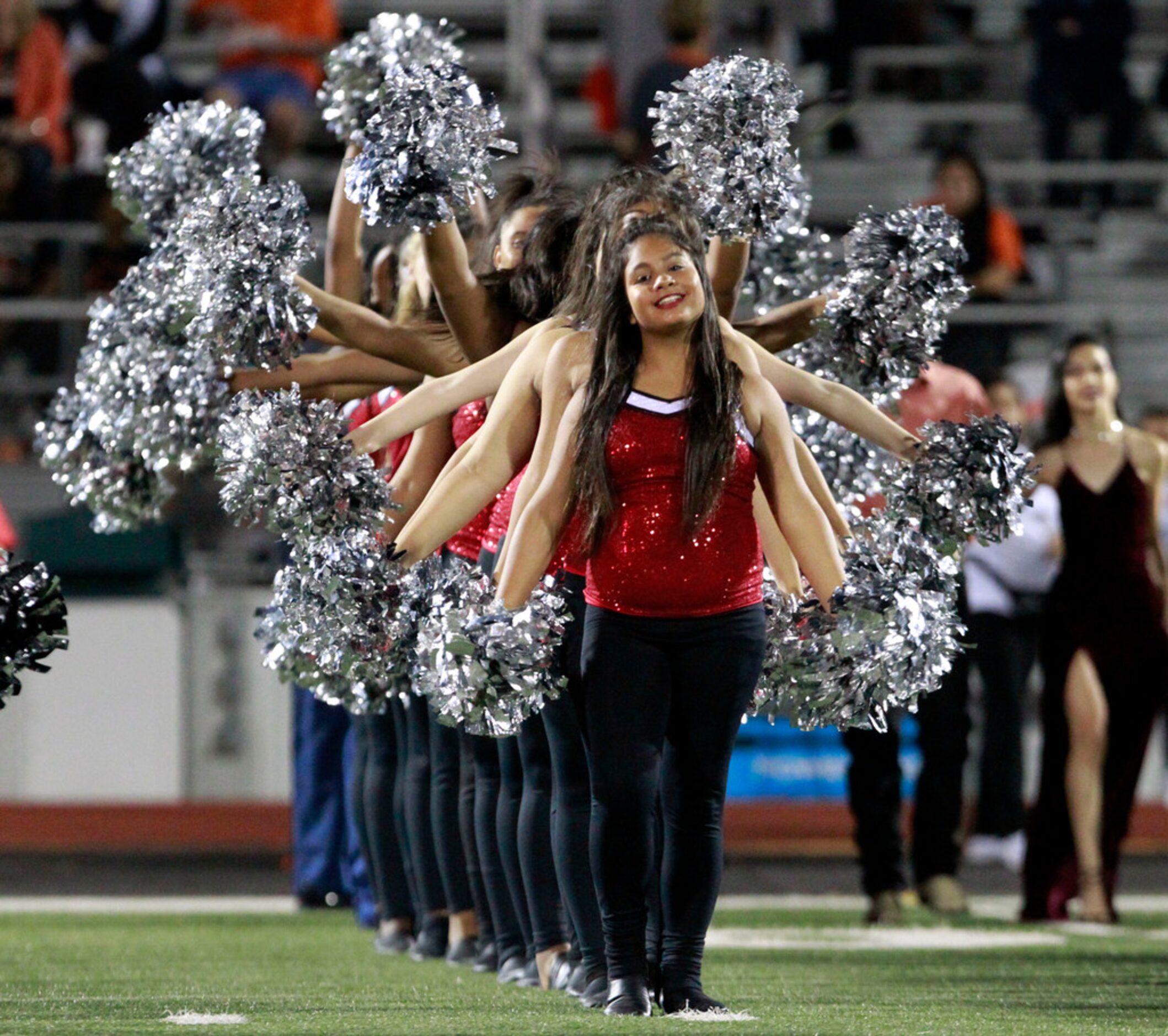 The Mesquite Horn drill team performs contagions with silver poms before the start of a high...