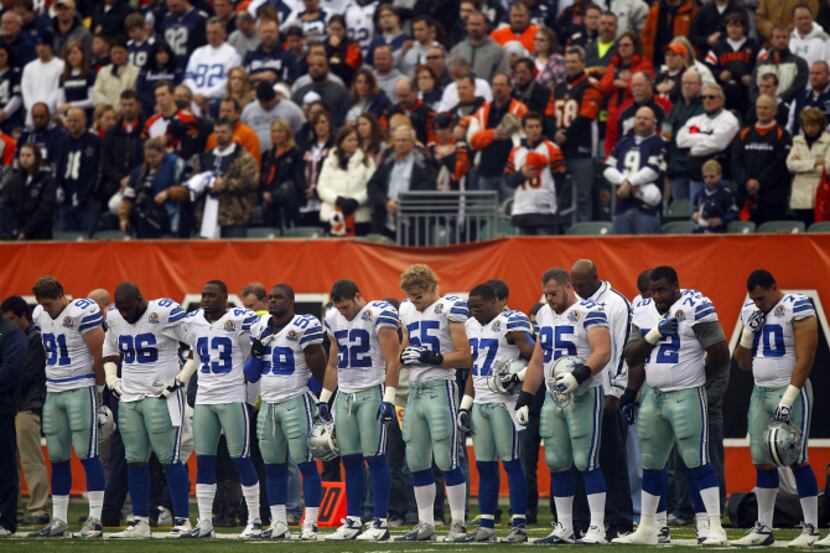 The Dallas Cowboys bow their heads during a moment of silence for their teammate Jerry Brown...