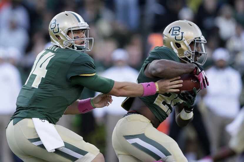 Baylor quarterback Bryce Petty (14) hands off to running back Lache Seastrunk, right in the...