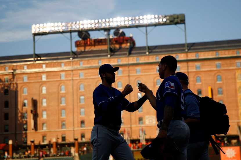 Members of the Texas Rangers fist-bump before a baseball game against the Baltimore Orioles...