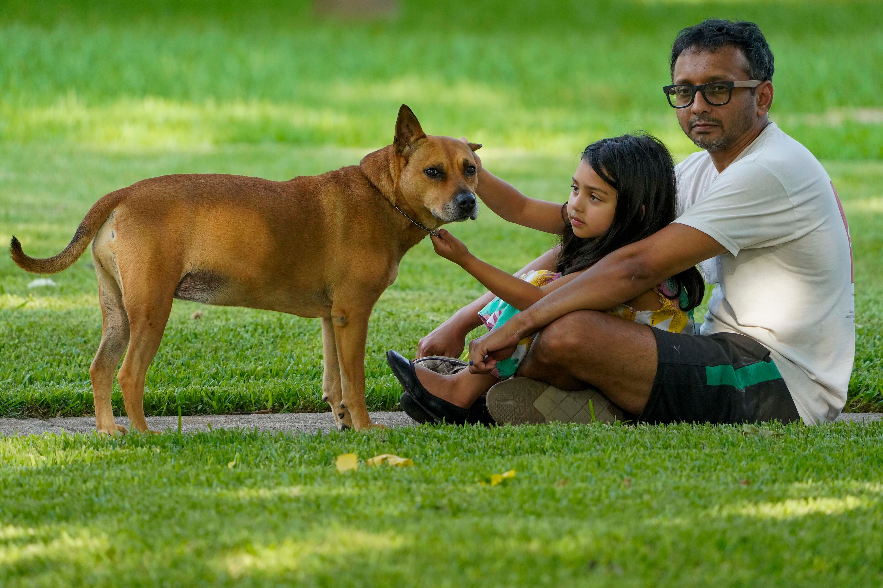 Shomik Pathak sits with his daughter Mira, 5, and their dog Bindi as they listen to Cameron...
