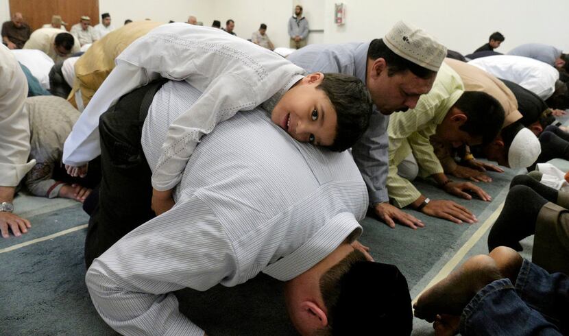 Subhan Latif, 4, rests on his father, Zubair Latif,  during a prayer service for...