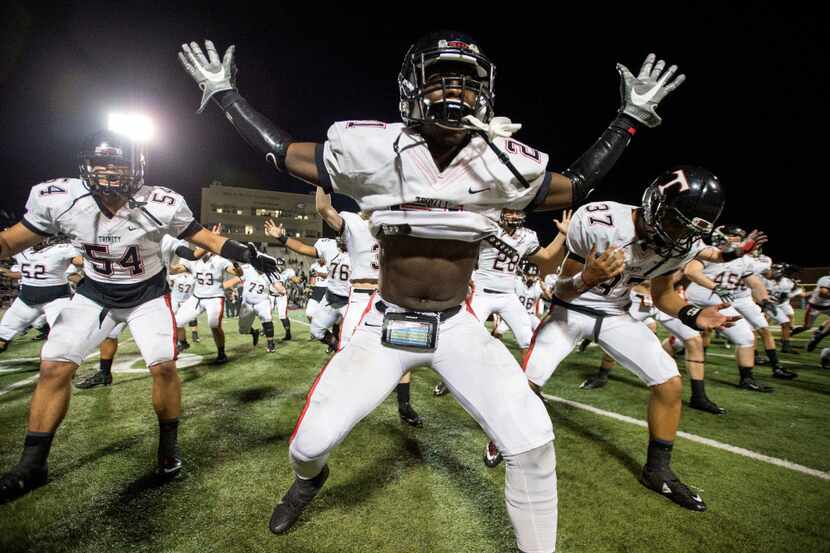 Euless Trinity junior running back Courage Keihn (21) celebrates with his teammates by doing...