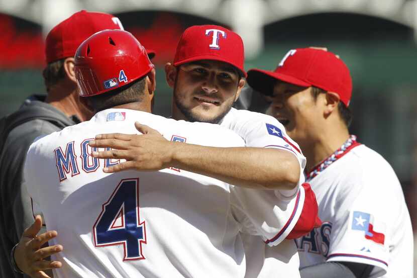 Texas Rangers starting pitcher Martin Perez (33) celebrates by hugging first base coach...
