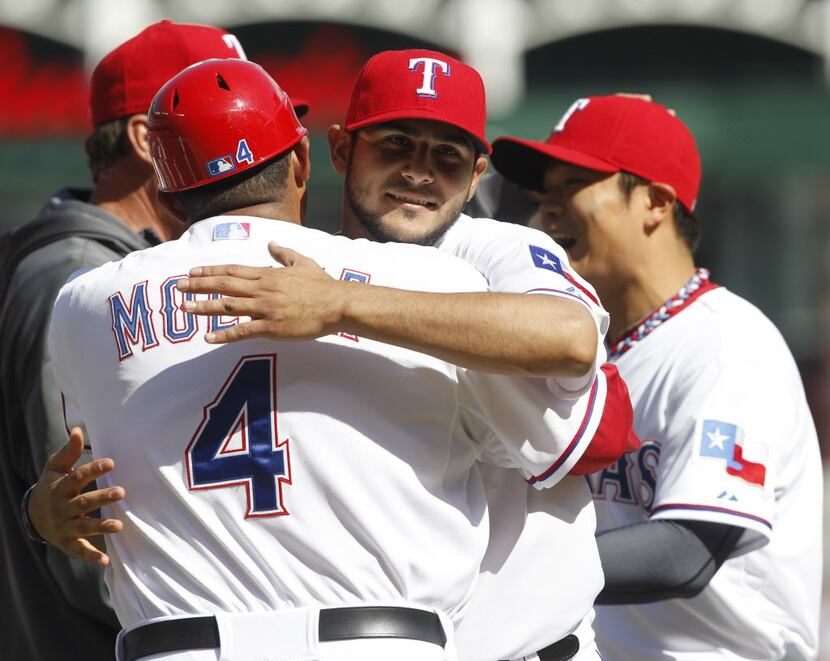 Texas Rangers starting pitcher Martin Perez (33) celebrates by hugging first base coach...