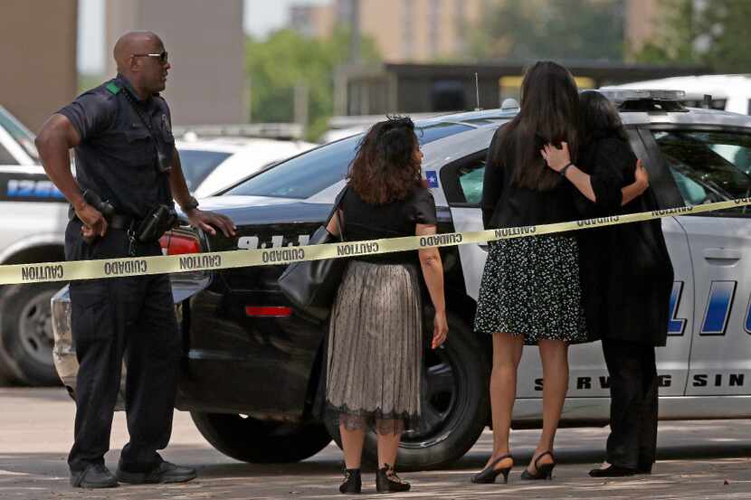 Workers console one another after police evacuated an office building in Lake Highlands near...