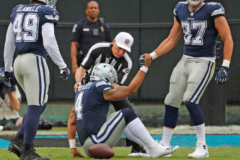 Dallas Cowboys quarterback Dak Prescott (4) is helped to his feet by tight end Geoff Swaim...